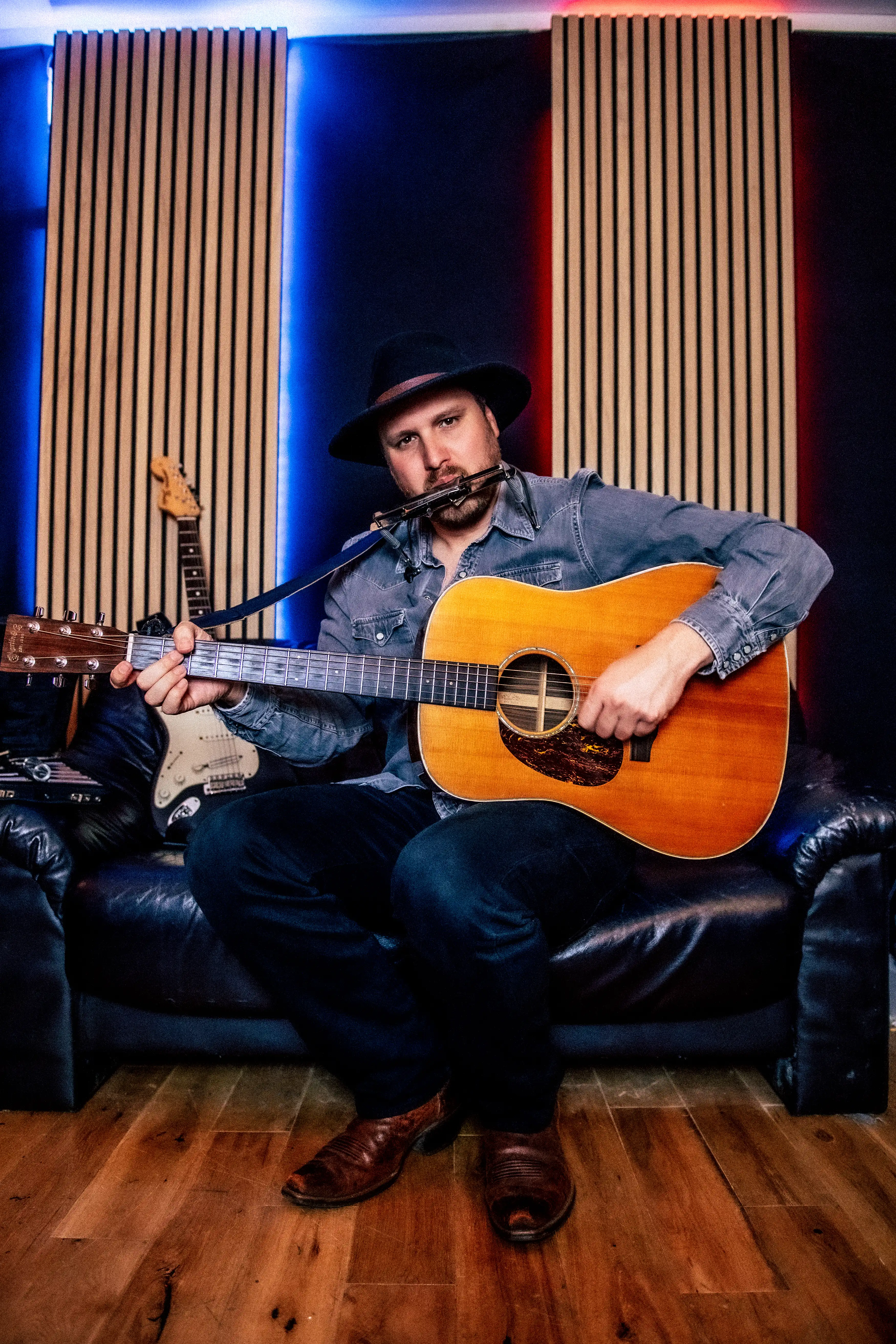 Ben Joseph sitting on a couch with his guitar